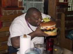 chico de color comiendo gran hamburguesa